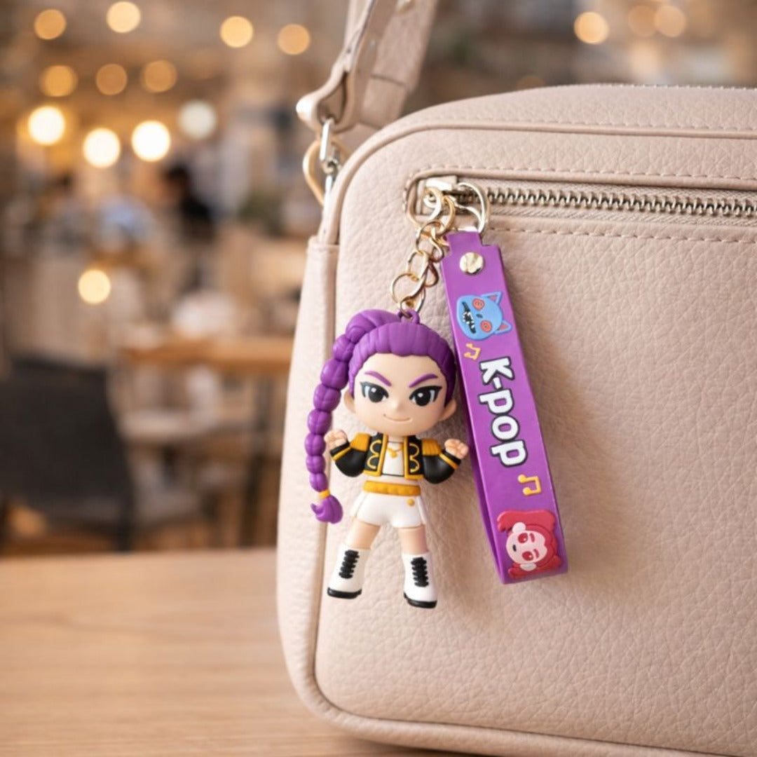 Keychain with a character and 'K-Pop' tag attached to a beige bag in an indoor setting.

