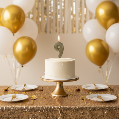 Golden glitter number 9 candle lit on white frosted birthday cake with gold balloons